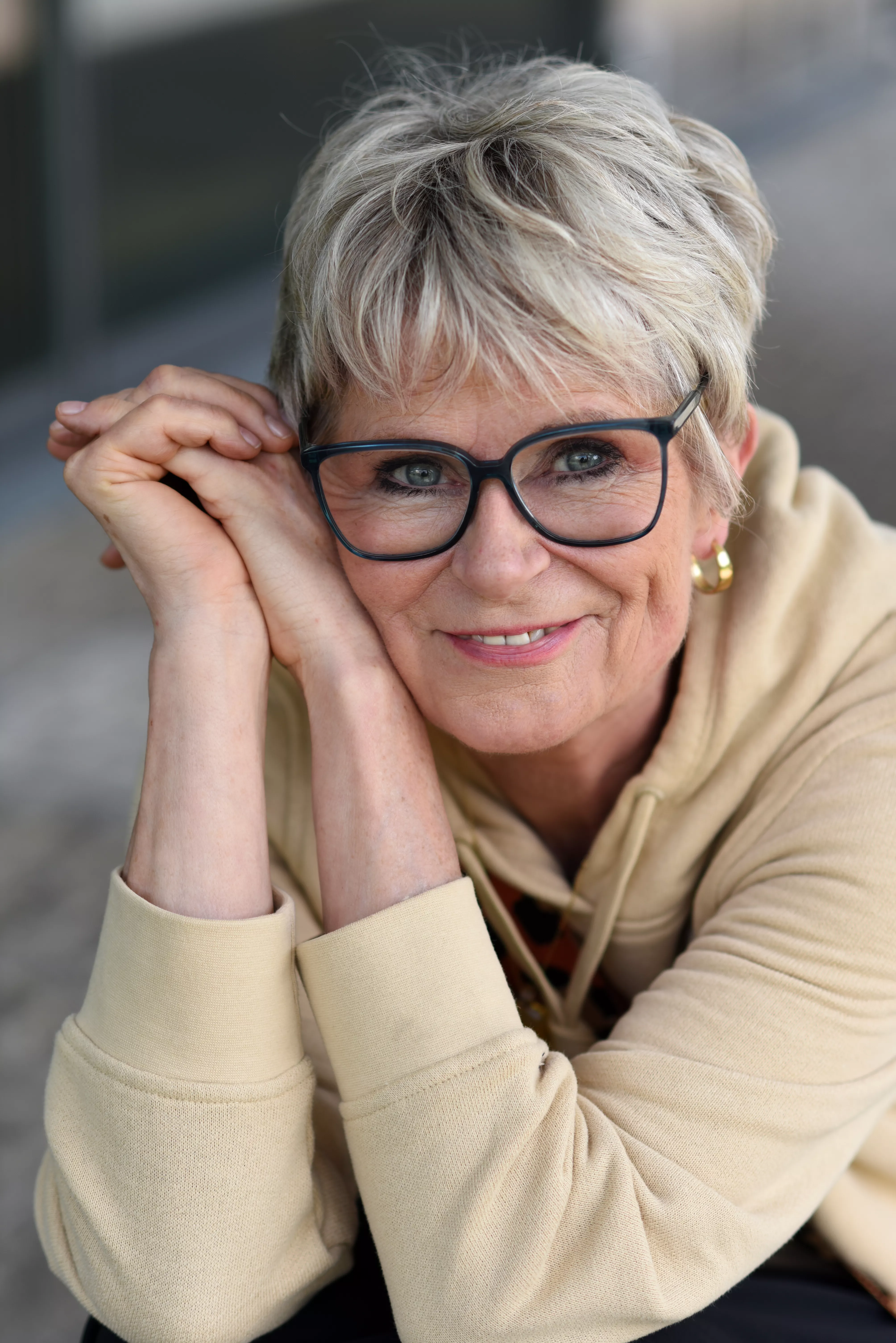 Bettina lächelt dich an, die Hände gekreuzt und abgestützt
