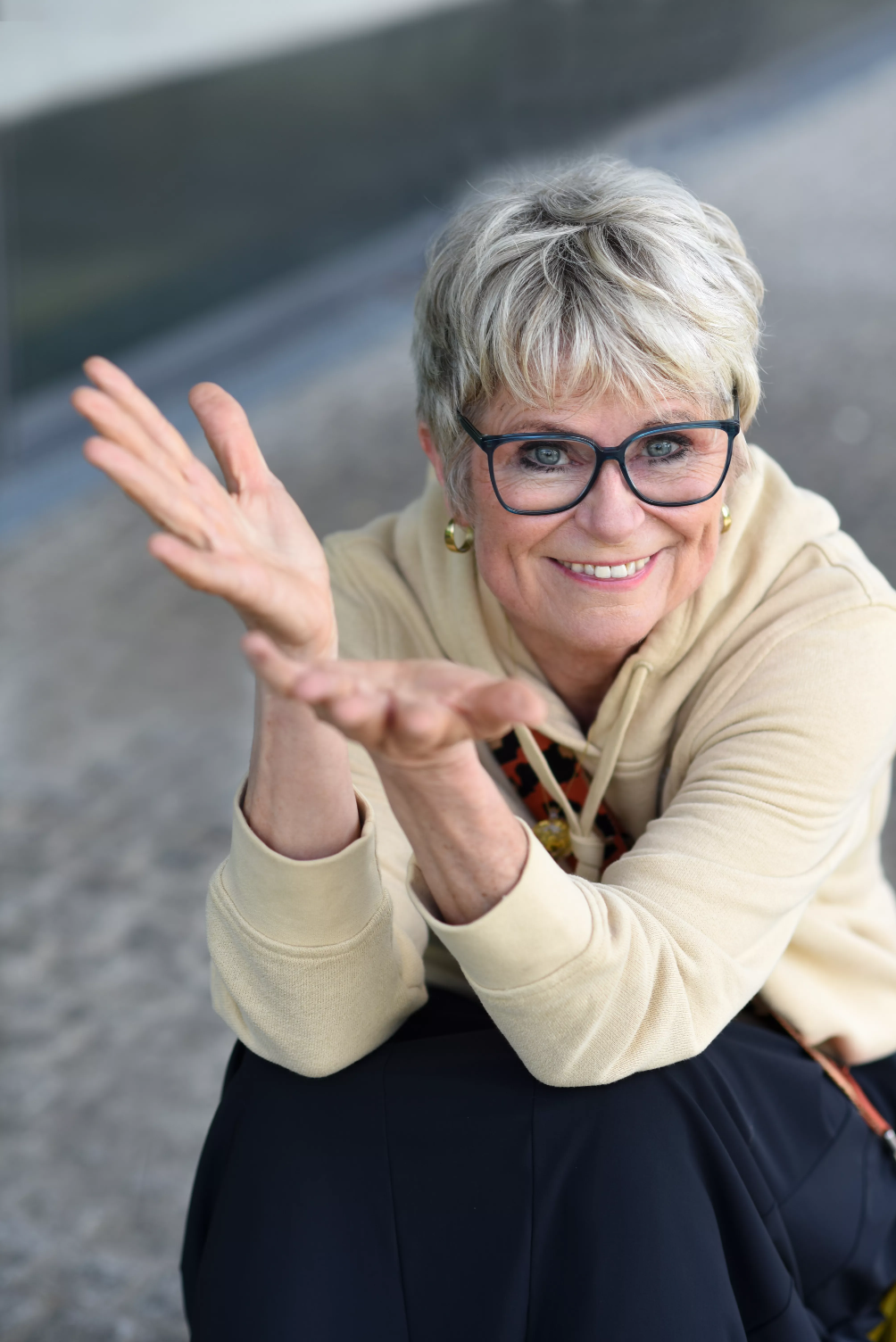 Bettina schaut dich lächelnd an, die Hände mit einladender Geste